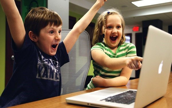 Usability Testing of Software:Two kids raising their arms joyfully in front of a computer, showing enthusiasm and satisfaction.