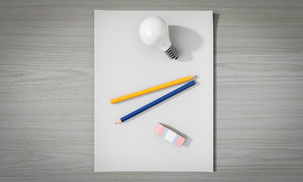 Sheet of paper, pencils, and a light bulb, symbolizing creativity and the generation of ideas.