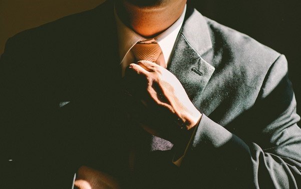 Jefe de Producto: Un hombre enchaquetado ajustándose la corbata, listo para una reunión.