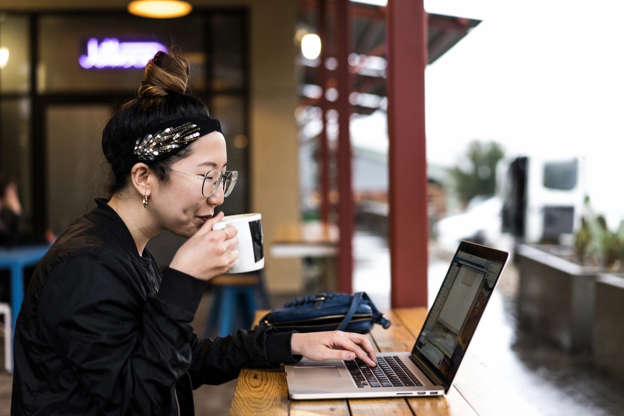 Woman enjoying a coffee while browsing the internet on her computer.