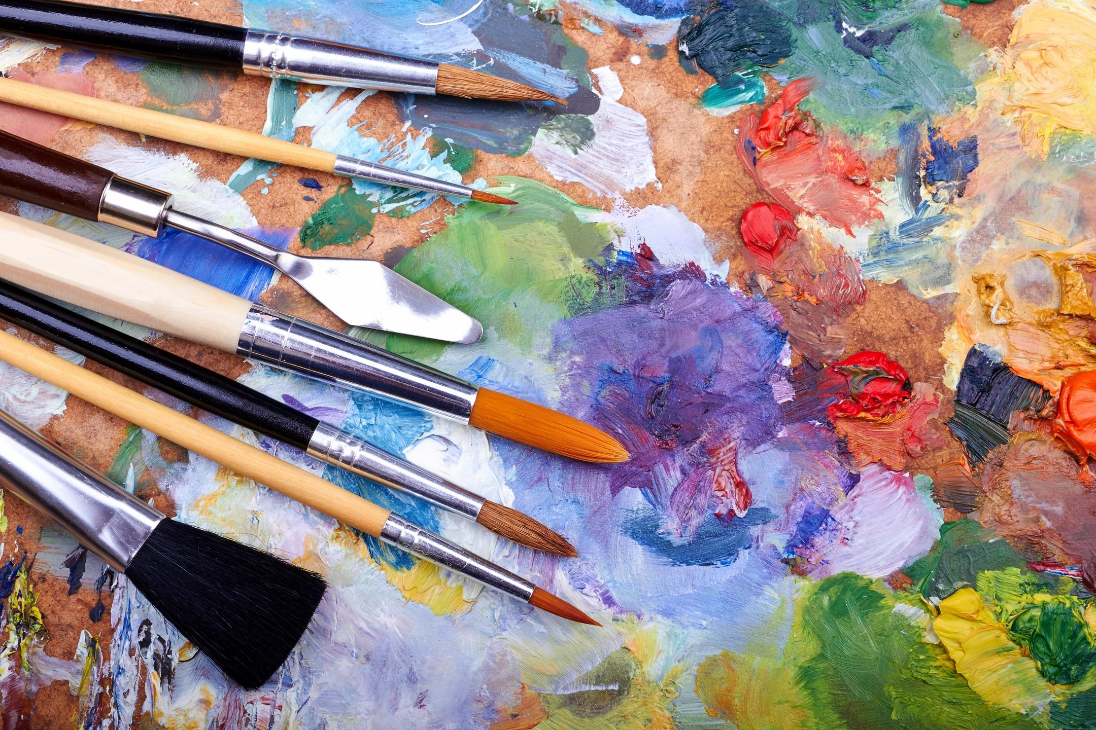 Brushes and a sheet of paper with paint colors on a table.